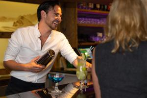 a man preparing a drink at a bar with a woman at Mountainclub Hotel Ronach in Königsleiten
