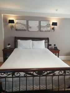 a bedroom with a large bed with four pictures on the wall at The Tudor Hotel in Harrow