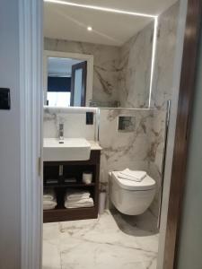 uma casa de banho com um lavatório, um WC e um espelho. em The Tudor Hotel em Harrow