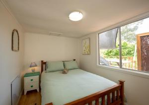 a small bedroom with a bed and a window at Delphi, Adelaide Hills Garden BnB in Mylor