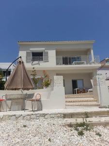 a house with two chairs and an umbrella in front of it at Villa Elsi upper apartment in Kalami