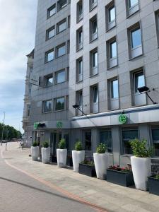 un bâtiment avec des pots blancs de plantes devant lui dans l'établissement elaya hotel hannover city, à Hanovre