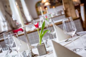 una mesa con copas de vino y una flor roja en un jarrón en Mountainclub Hotel Ronach en Königsleiten