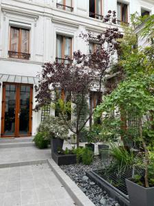 un bâtiment avec des arbres et des plantes devant lui dans l'établissement MaisonZen, à Paris