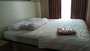 a white bed with two pillows and a purse on it at Apartemen Borneo bay city in Balikpapan