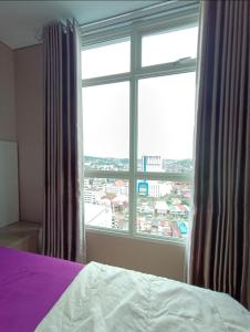 a bedroom with a bed and a large window at Apartemen Borneo bay city in Balikpapan
