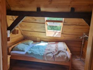 a bed in a wooden room with a window at Dom wakacyjny nad jeziorem Jodłów in Nowa Sól