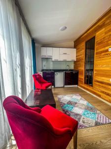 a living room with two red chairs and a kitchen at Mego Suite Otel in Uzungöl