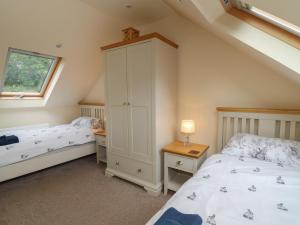 a bedroom with two beds and a cabinet and a window at Gelli Barn in Llandeilo