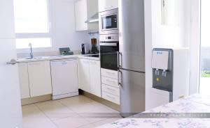 a kitchen with white cabinets and a stainless steel refrigerator at Royal Dream Villas in Adeje