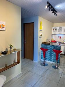 a kitchen with red stools in front of a counter at Quarto - Nosso lar em Natal in Natal