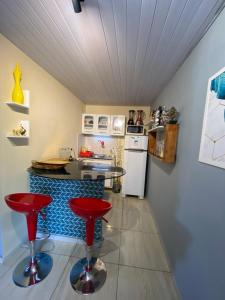 a kitchen with a counter and red stools in it at Quarto - Nosso lar em Natal in Natal +19 photos