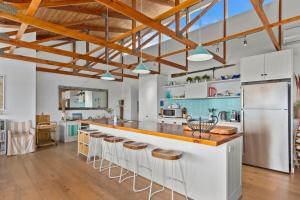 a kitchen with white cabinets and a counter with stools at Stones Throw 26 River View Drive in Normanville