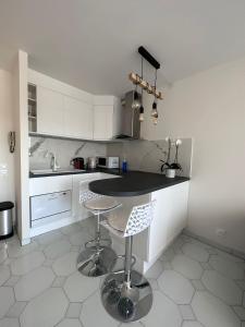 a kitchen with white cabinets and a table and stools at Studio Antibes Port Vauban. in Antibes