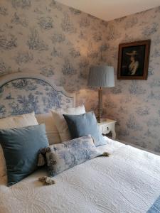 a bedroom with a bed with blue floral wallpaper at Merriman Cottage in Chipping Campden