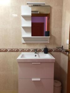 La salle de bains est pourvue d'un lavabo blanc et d'un miroir. dans l'établissement Apartamento muy cerca de la playa, à Villanueva de Arosa