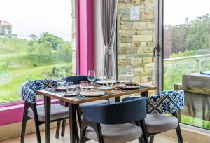 una mesa con copas de vino y sillas frente a una ventana en Abba Comillas Hotel, en Comillas