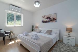 a white bedroom with a bed and a chair at Beachfront Apartment with parking in Slatine