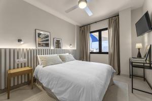 a white bedroom with a bed and a window at La casa de las velas in Playa Honda