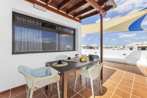 een patio met een tafel en stoelen en een groot raam bij La casa de las velas in Playa Honda