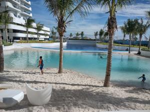a swimming pool with palm trees on a beach at Pampanga Staycation Condo Unit In San Fernando in San Fernando