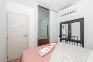 a bedroom with a bed with a pink blanket and a window at Apartmani Tona in Baška Voda