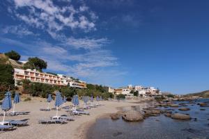 a beach with chairs and umbrellas on a beach at Creta Mare Hotel in Plakias