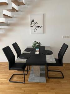 una mesa de comedor con sillas negras y una escalera en Paky Appartements 00316, en Bruck an der Leitha