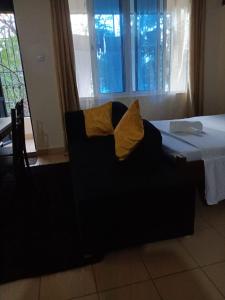 a black chair with yellow pillows sitting next to a bed at Mkombodzi Global Homes in Mtwapa