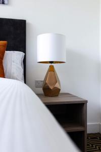 a lamp on a table next to a bed at Flatzy - 16 Guests 4 En-suite Central Apartment A in Liverpool