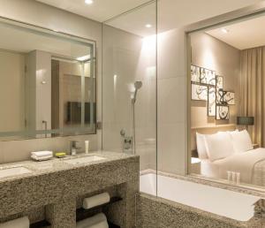 a bathroom with a sink and a tub and a bed at Le Méridien City Centre Bahrain in Manama