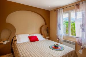um quarto com uma cama com uma almofada vermelha e uma janela em U Guadellu - Piscine Chauffée em Oletta