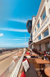 a hotel with tables and chairs on the beach at Belgische Loodsensociëteit in Vlissingen