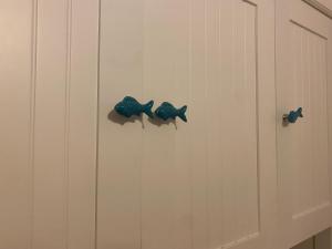 three blue fish hooks on a white wall at Sunshine House in Porto Pino