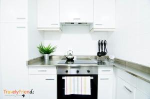 cocina con armarios blancos y fogones negros en Spacious & Central Apartament en Santiago de Compostela