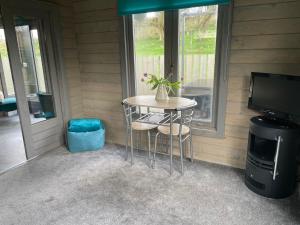 a small table with two stools in front of a window at Daisy Cabin in Kincardine OʼNeil