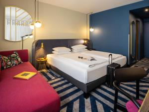 a bedroom with a large bed and a red couch at Hotel Mercure Wien City in Vienna