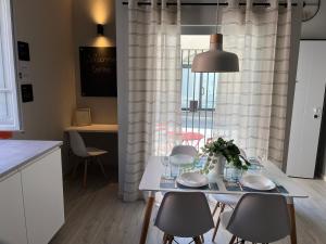 een witte tafel en stoelen in een keuken met een raam bij Maremma Holidays : La Vecchia Officina in Follonica