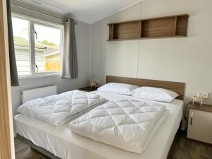 ein Schlafzimmer mit einem Bett mit weißen Laken und einem Fenster in der Unterkunft Chalet 572 op Recreatiepark De Wielen in Sint Maarten + 20 Fotos