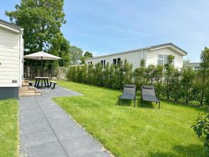 einen Garten mit zwei Stühlen, einem Tisch und einem Sonnenschirm in der Unterkunft Chalet 572 op Recreatiepark De Wielen in Sint Maarten