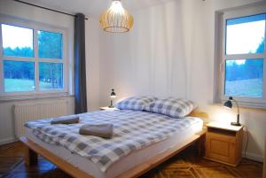 a bedroom with a large bed with two windows at Ośrodek wypoczynkowy Jezioro in Studzienice