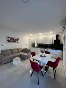 sala de estar con mesa blanca y sillas rojas en Apartments Luce - Dome, en Split