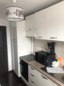 a kitchen with white cabinets and a black microwave at Vibe apartament in Piatra Neamţ
