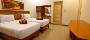 een hotelkamer met twee bedden met bloemen erop bij Kubuku Eco Dive Lodge and Yoga in Pemuteran