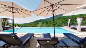 a swimming pool with chairs and umbrellas next to a pool at Villa Bambi in Mošćenička Draga