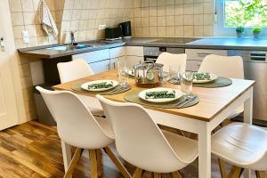 cocina con mesa de madera y sillas blancas en Worker suite in Niefern-Öschelbronn near Pforzheim, en Niefern-Öschelbronn