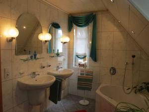 a bathroom with two sinks and a tub and a mirror at Ferienwohnung Yuan in Bruchweiler-Bärenbach