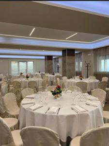 un salón de banquetes con mesas blancas y sillas blancas en Santangelo Hotel, en Monte SantʼAngelo