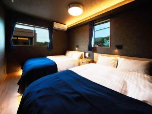 two beds in a room with two windows at Rakuten STAY HOUSE Kujukuri Ichinomiya 103 3LDK with BBQ terrace in Ichinomiya