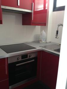 a kitchen with red cabinets and a black oven at Apartamento Paco in Playa del Ingles